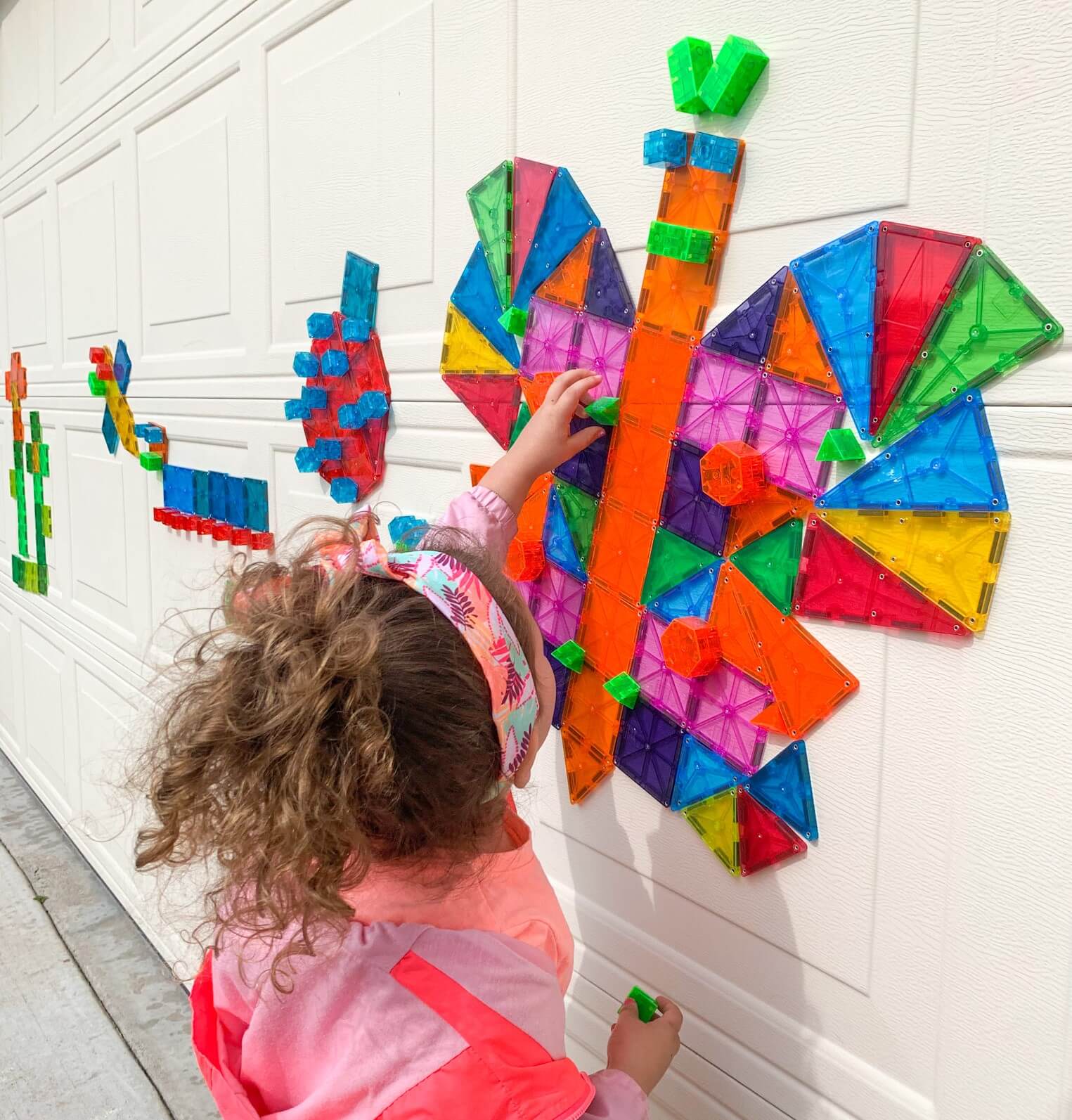 Little girl using her imagination to build a butterfly with Magna-Tiles