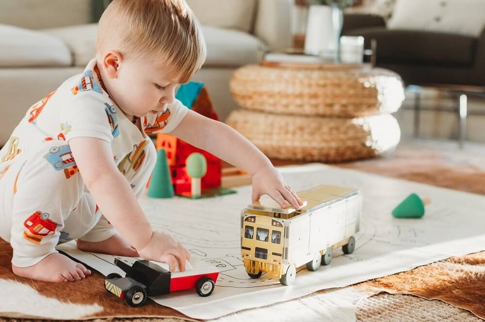 Little boy playing with a car & school bus created with Magna-Tiles Structures