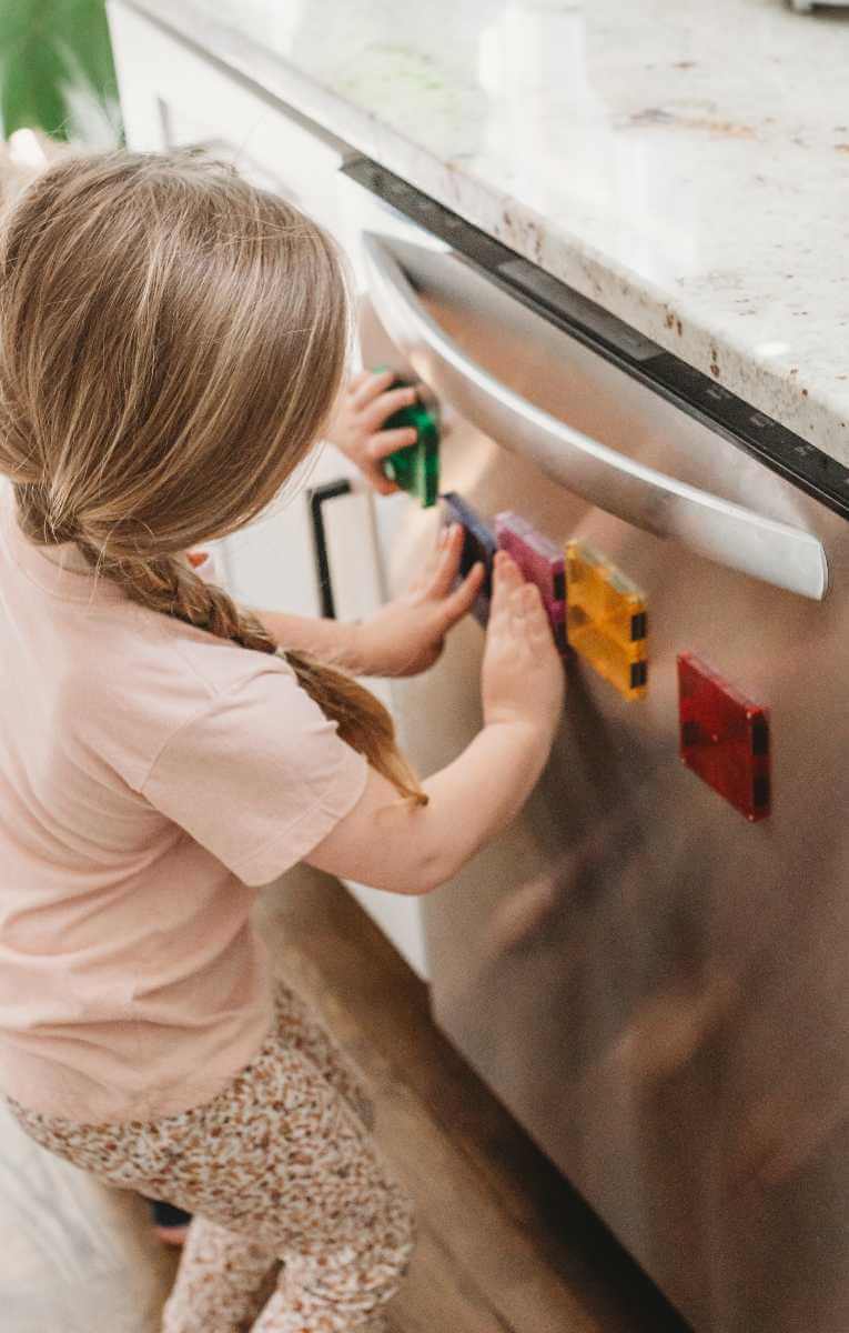 Child playing with Magna-Tiles on a dishwasher