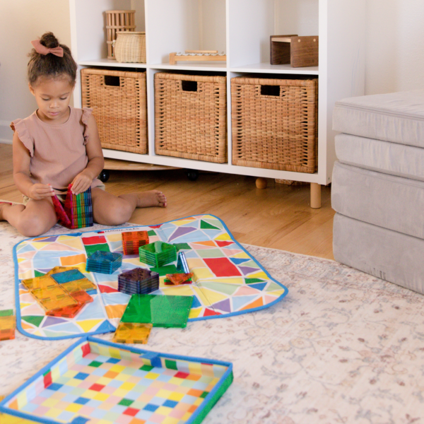 Young girl playing with MAGNA-TILES® on the 2-in-1  Storage Bin & Interactive Play-Mat