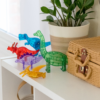 Blue T-Rex, green Brachiosaurus, red Triceratops, purple Stegosaurus, and yellow Pteranodon from MAGNA-TILES® Dinos 5-Piece Set sitting on a shelf.