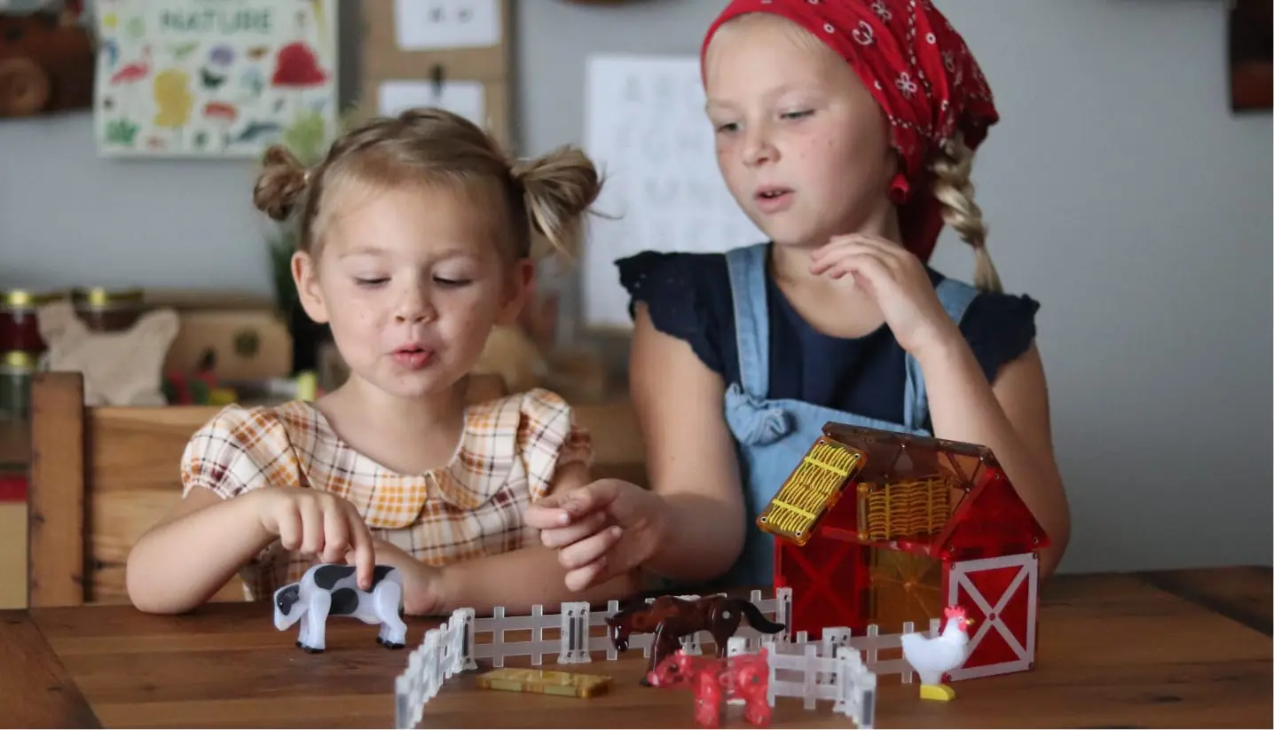 Two young girls playing with MAGNA-TILES® Farm 25-Piece Set